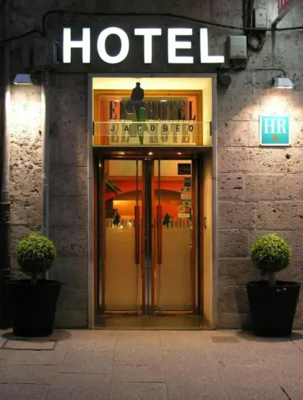 Entrada del hotel de noche, con cartel iluminado de
