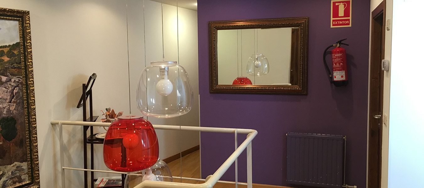 Una pared morada con un espejo y un extintor en un pasillo.