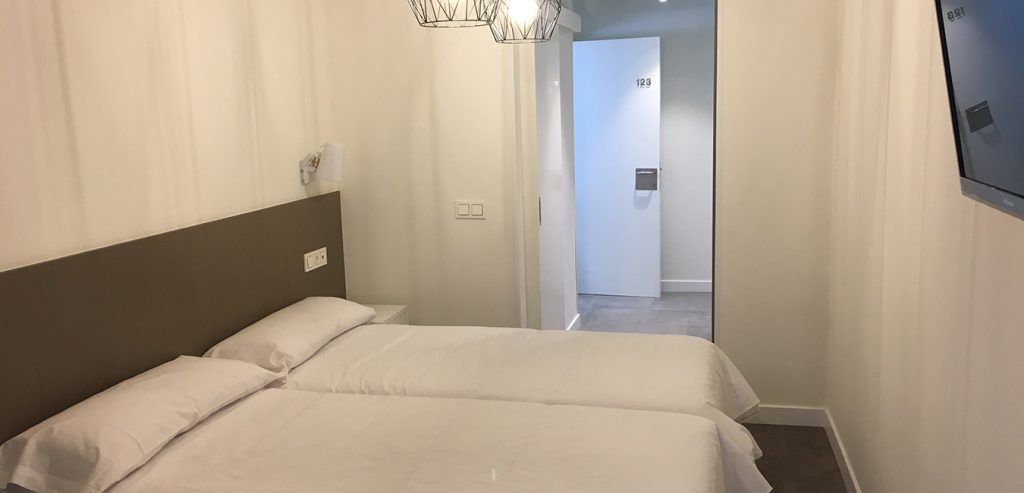 Un dormitorio con dos camas y un televisor en la pared.