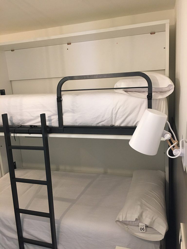 Una litera con una escalera y una lámpara encima.