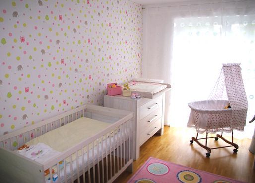 Ein Babyzimmer mit Kinderbett, Wickeltisch und Schaukelstuhl.