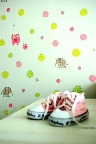 Ein Paar rosa Schuhe steht auf einem Tisch vor einer Wand mit Tupfen und Elefanten darauf