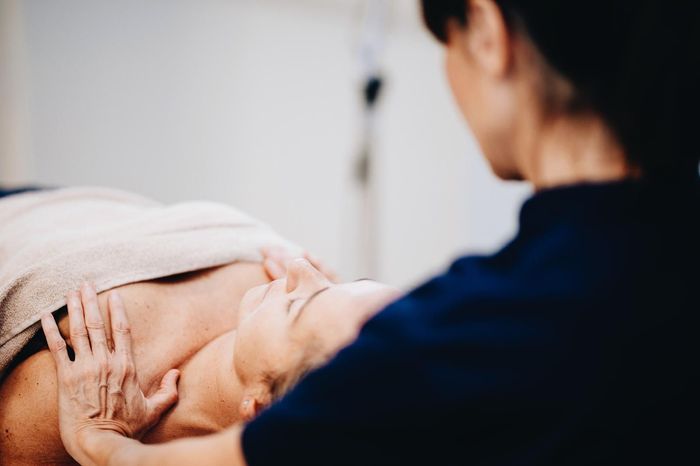Persona recibiendo tratamiento facial; manos del terapeuta sobre el rostro, expresión relajada.