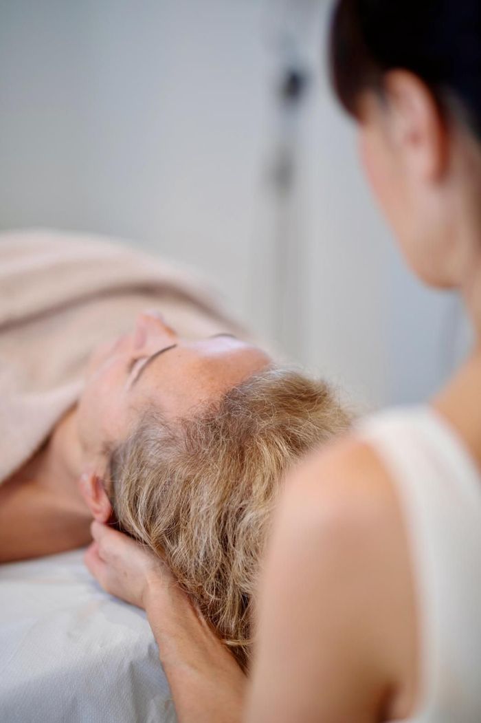 Persona recibiendo un masaje de cabeza de otra persona en un spa.