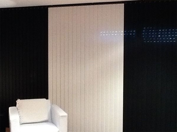 Un sillón blanco se encuentra frente a una pared con persianas verticales blancas y negras.