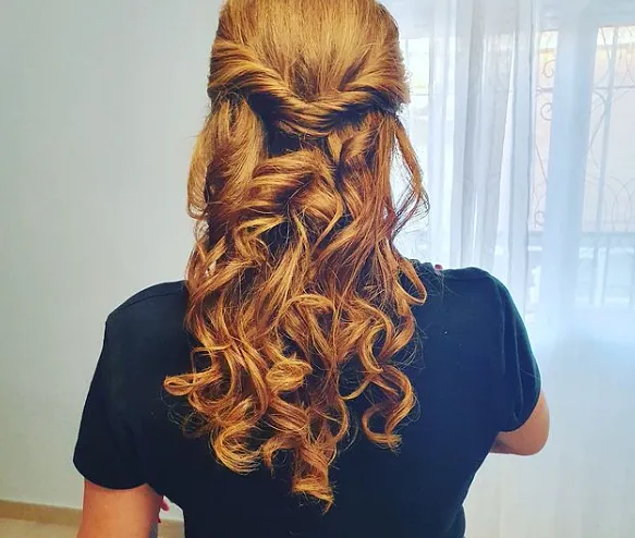 La mujer lleva una camisa negra y tiene el cabello recogido mitad arriba y mitad abajo.