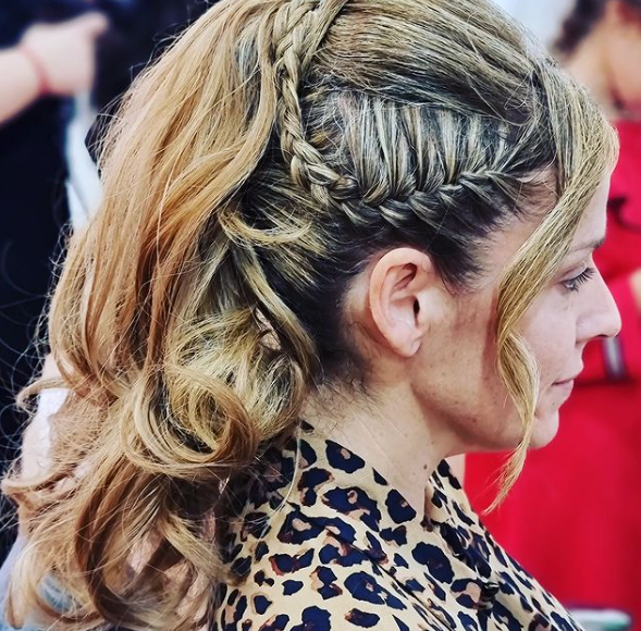 Una mujer con una cola de caballo trenzada lleva una camisa con estampado de leopardo.