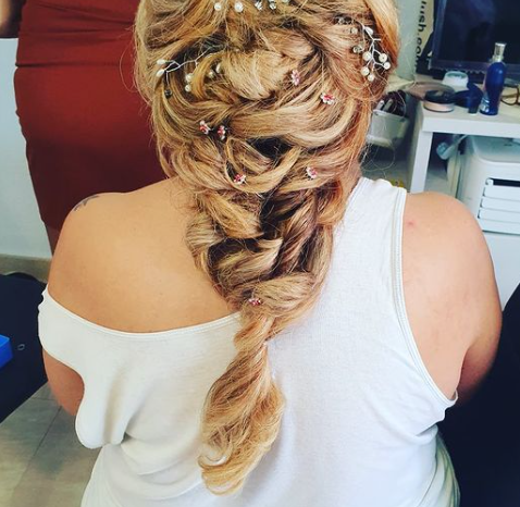 Una mujer que lleva una camiseta blanca sin mangas tiene el pelo recogido en una trenza.