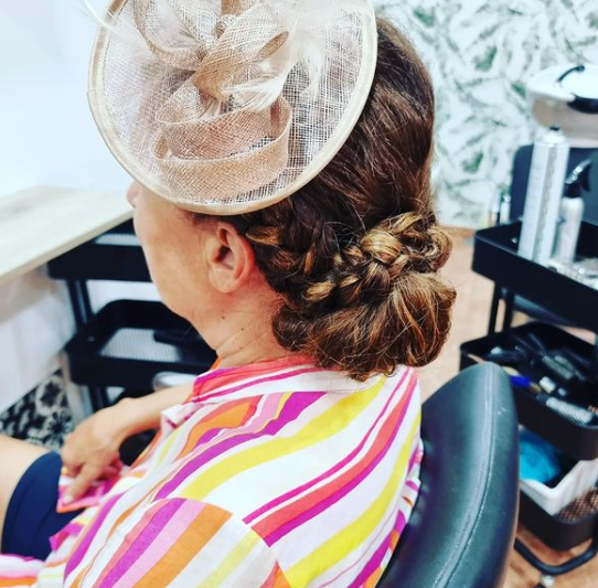 Una mujer que lleva una camisa a rayas y un sombrero está sentada en una silla.