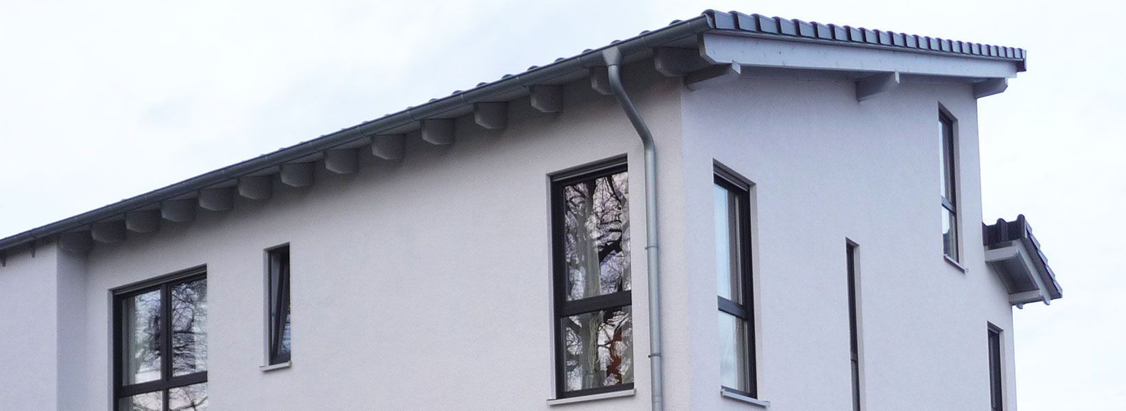 Ein weißes Gebäude mit schwarzen Fenstern und einem Ziegeldach