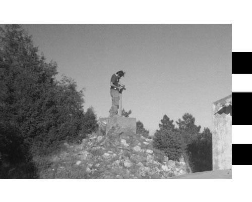 Una fotografía en blanco y negro de un hombre parado encima de una pila de rocas.