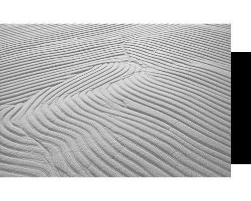 Una fotografía en blanco y negro de una playa de arena con olas.