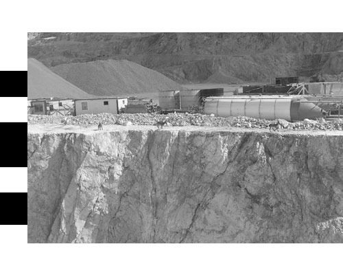 Una fotografía en blanco y negro de un acantilado con un edificio al fondo.