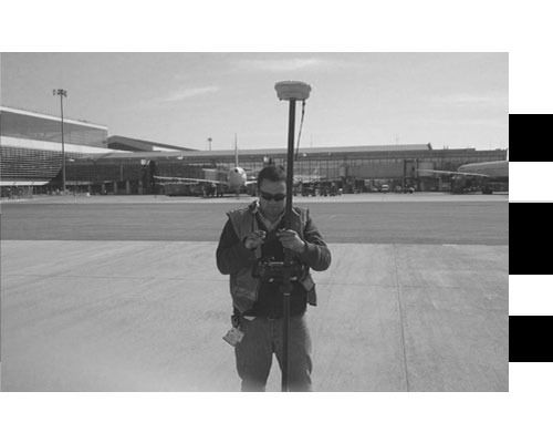 Una fotografía en blanco y negro de un hombre parado en la pista de un aeropuerto.