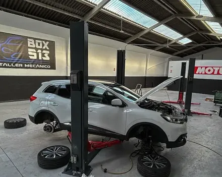 Un coche blanco está estacionado en un elevador en un garaje.
