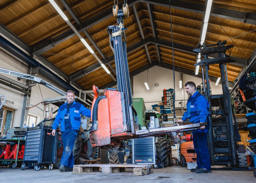 Zwei Mitarbeiter transportieren eine Gabel von einem Gabelstapler