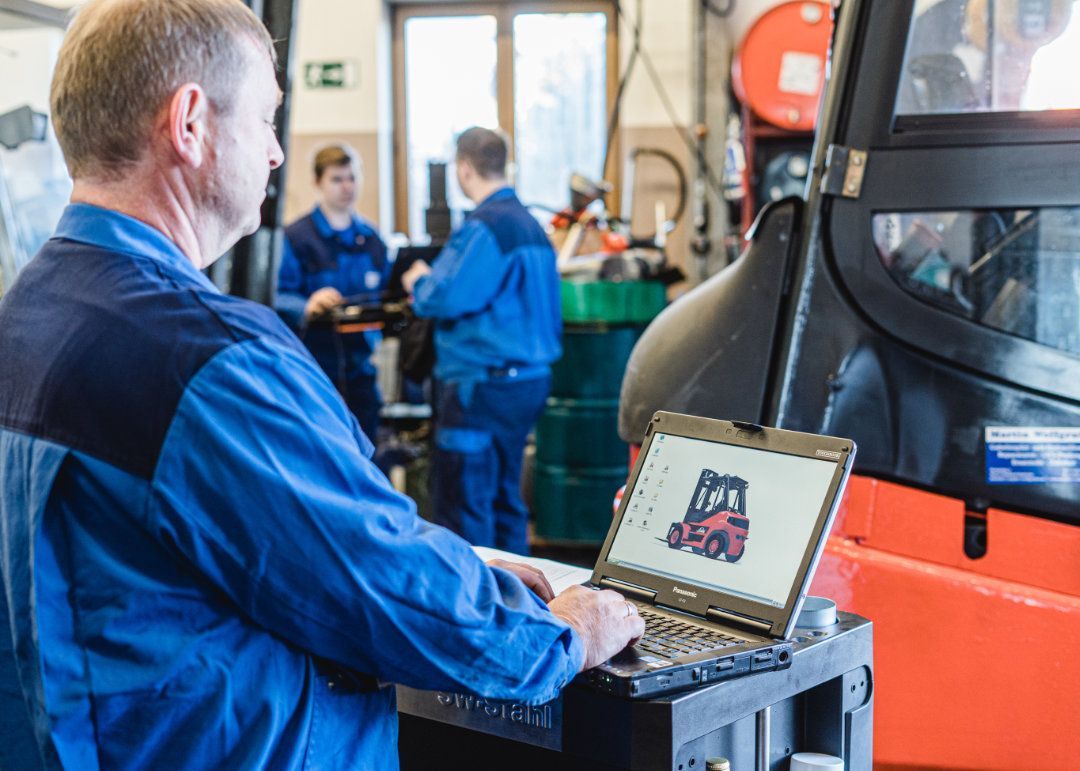 Mitarbeiter arbeitet an einem Laptop auf dem ein Gabelstapler abgebildet ist