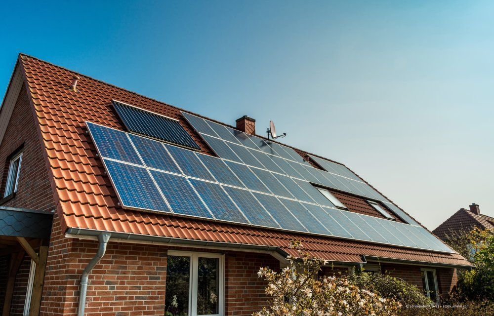 Hausdach mit Solarpaneelen unter klarem, blauem Himmel