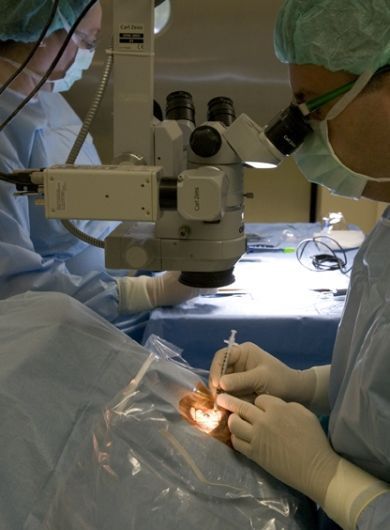 Un cirujano mira a través de un microscopio el ojo de un paciente.