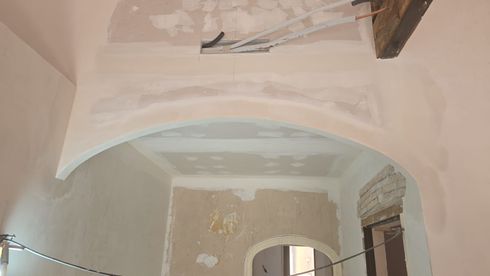 Interior con un gran techo abovedado en proceso de renovación, donde se aprecian parches de yeso