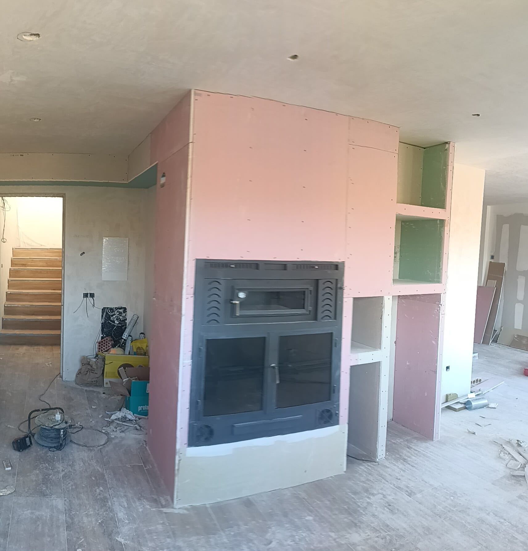 Habitación sin terminar con una chimenea empotrada de color rosa y estanterías