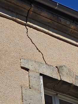 Bâtiment en stuc beige avec une porte de garage blanche et une petite fenêtre au-dessus.