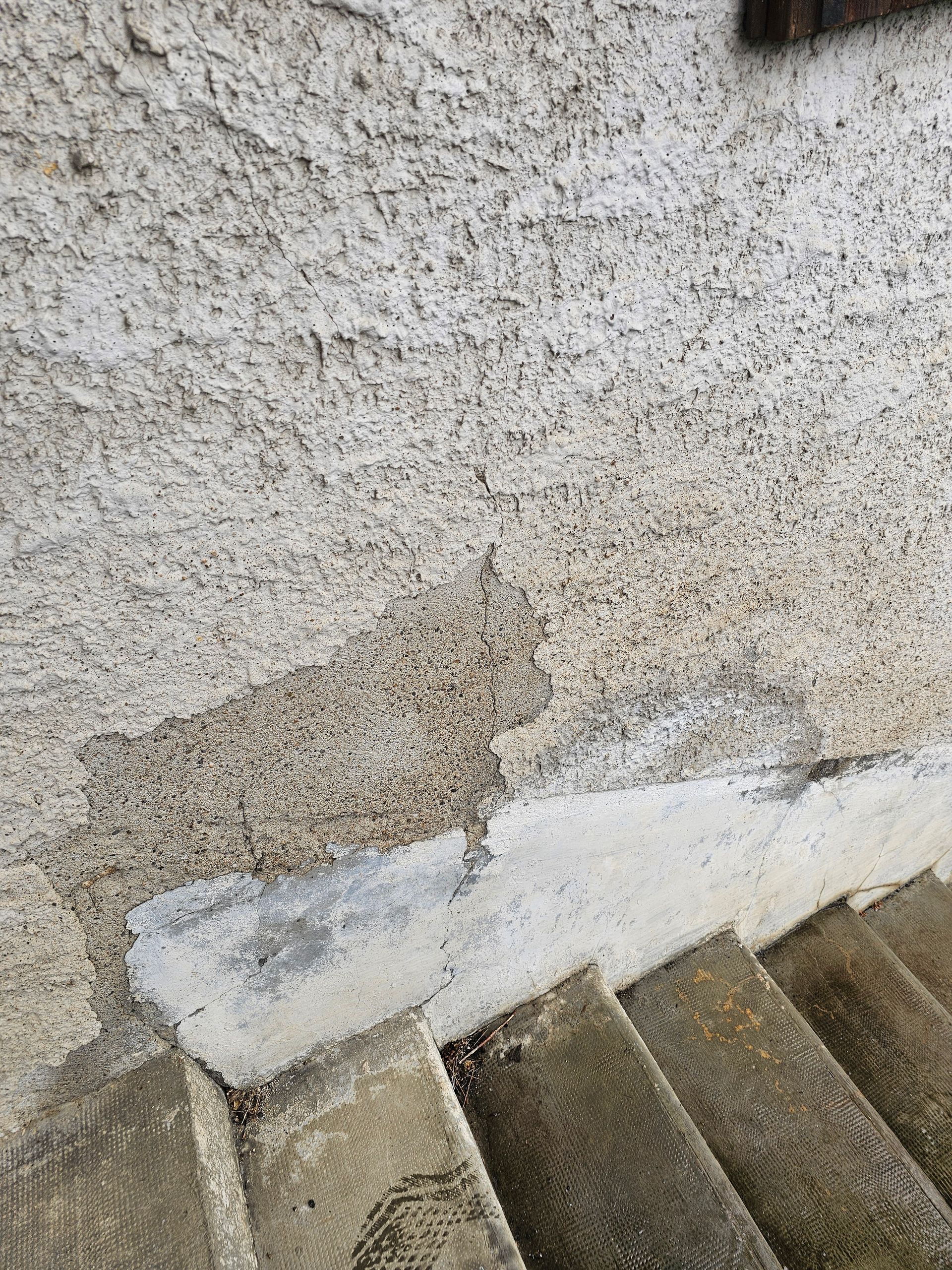 Mur en stuc défraîchi avec peinture blanche écaillée au-dessus d'escaliers en béton