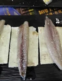 Filetes de pescado crudo sobre bloques blancos, dispuestos en una bandeja negra.