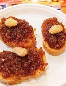 Tres pasteles cubiertos de almendras en un plato blanco.