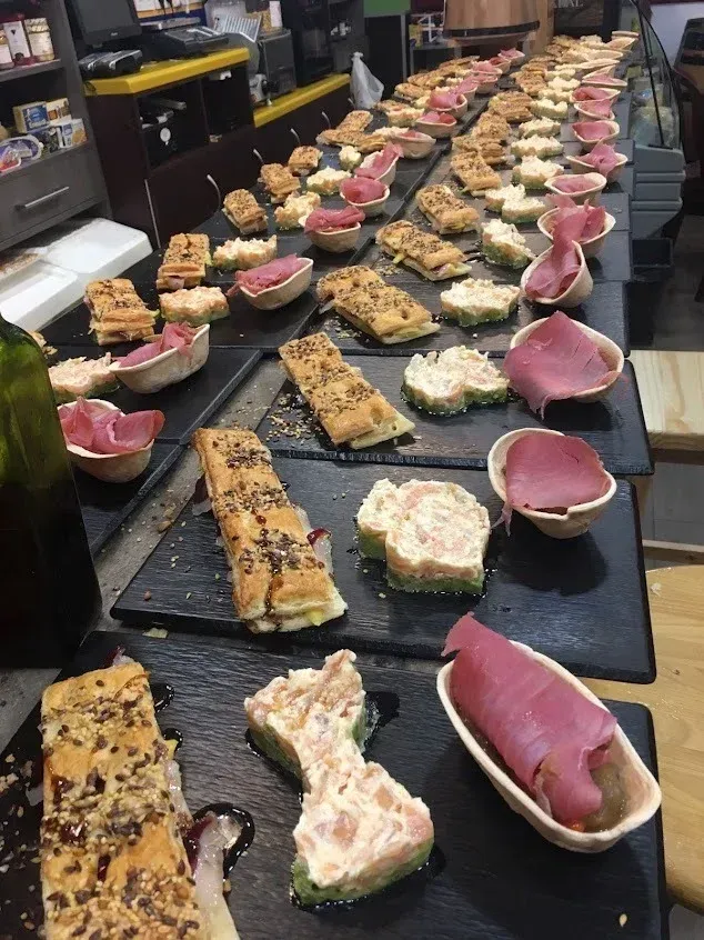 Filas de sushi y nigiri variados en bandejas negras en la cocina de un restaurante o en la zona de preparación de un bufé.