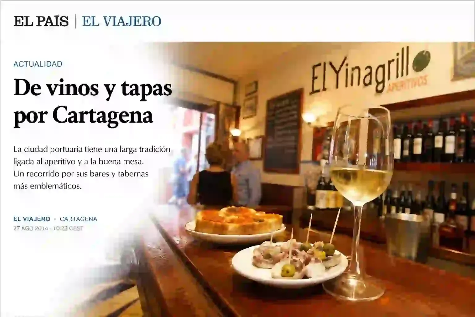 Tapas y vino en una mesa de bar en El Vinagrillo, un restaurante con un interior de tonos cálidos.