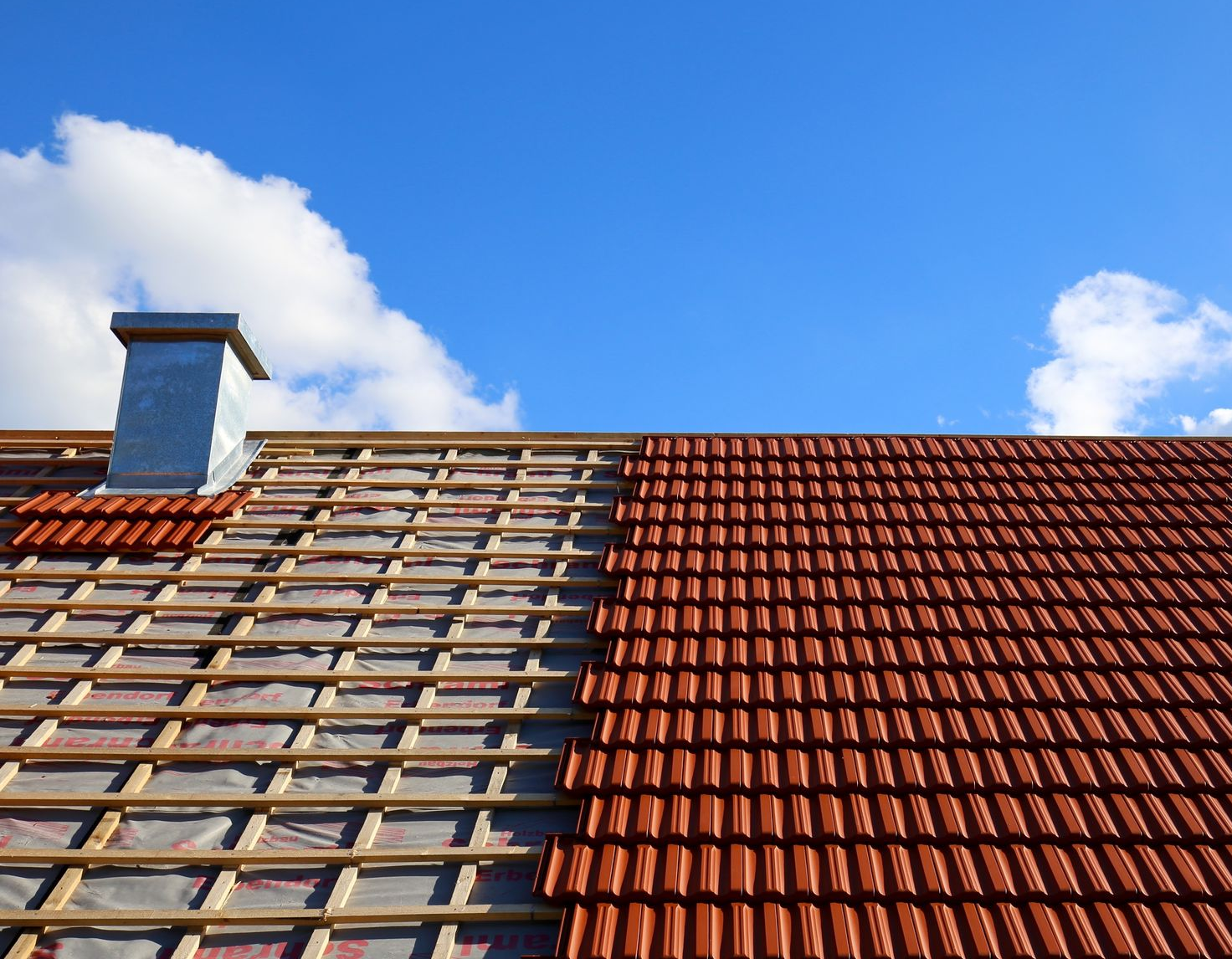 Un toit d'habitation partiellement recouvert de bardeaux et de tuiles.