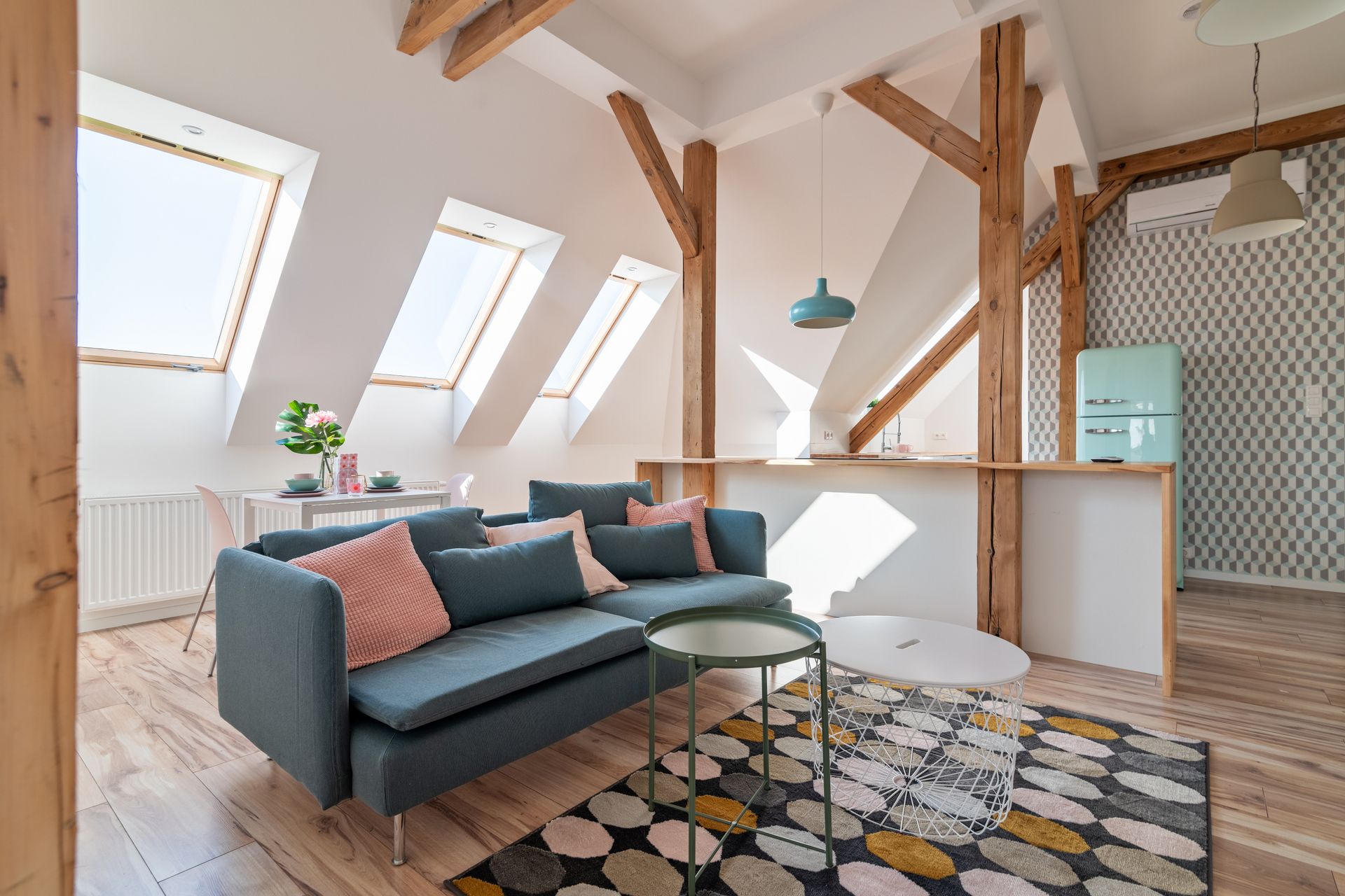 Un espace de vie moderne sous les combles éclairé par trois fenêtres de toit.