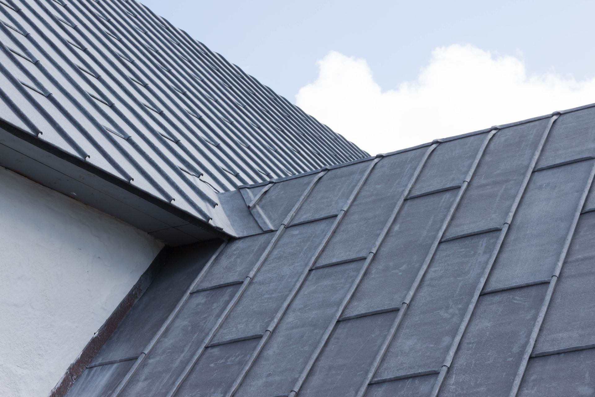 Vue en contreplongée de deux toitures métalliques grises.