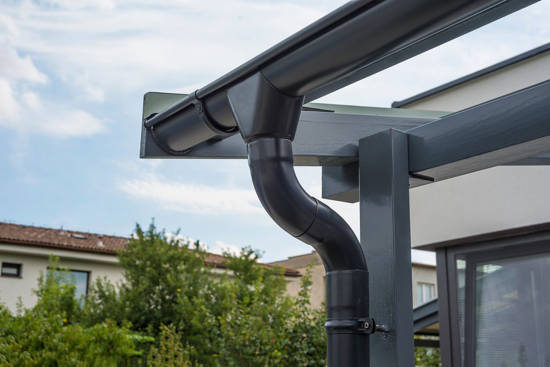 Gros plan sur une gouttière et un tuyau de descente modernes gris foncé.