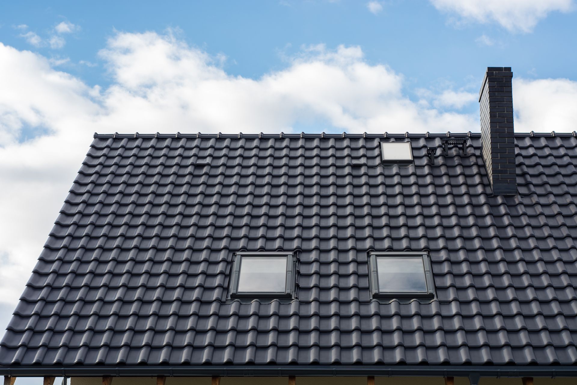 Un toit de tuiles sombres percé de deux puits de lumière.