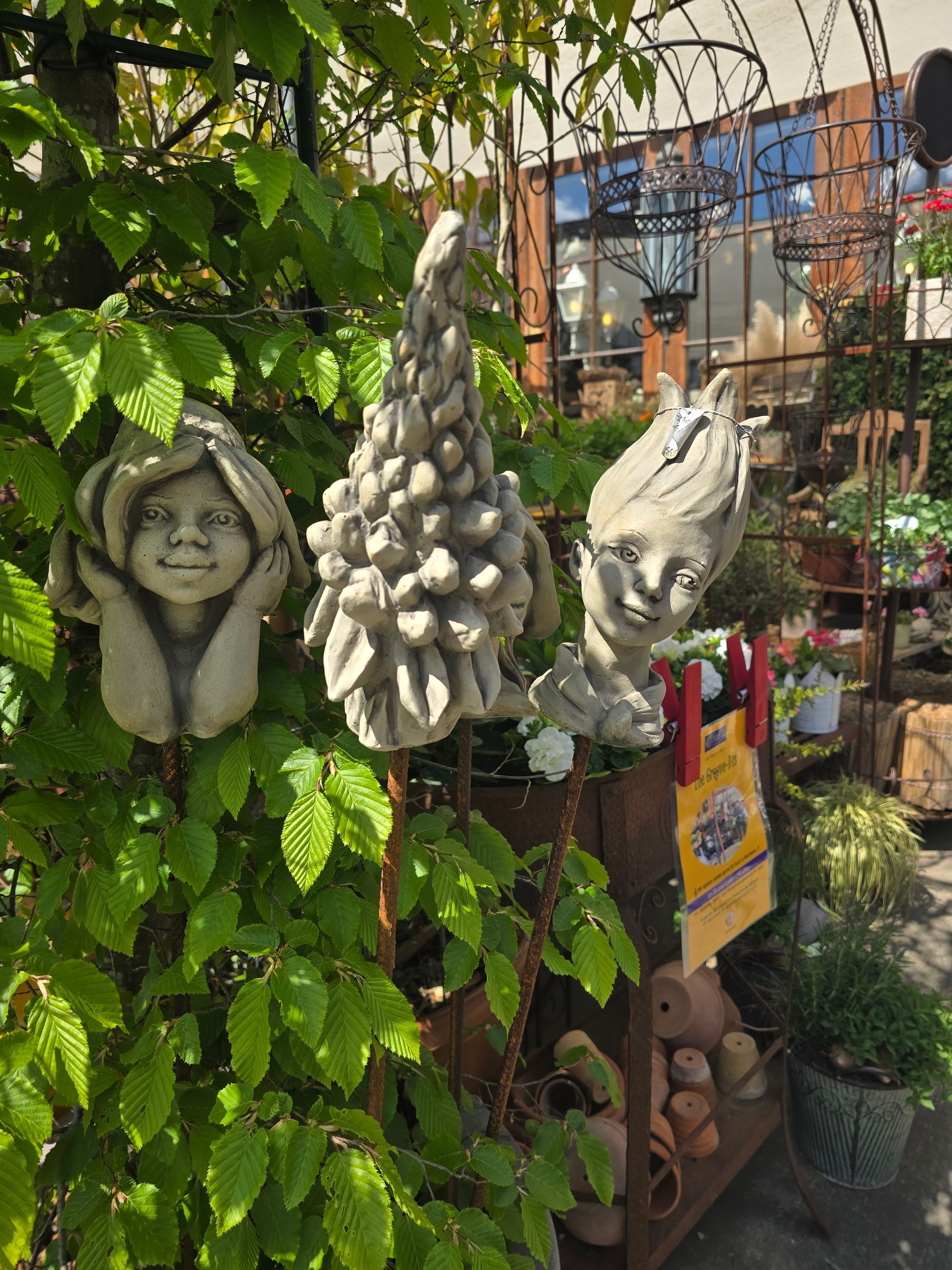 In einem Garten hängt die Statue eines Gnoms an einem Baum.