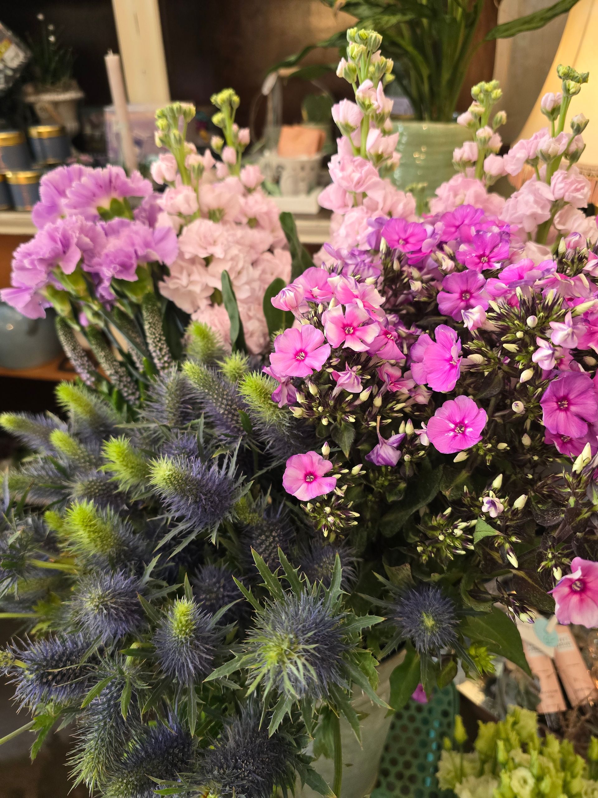 Auf einem Tisch steht ein Strauß lila und rosa Blumen.