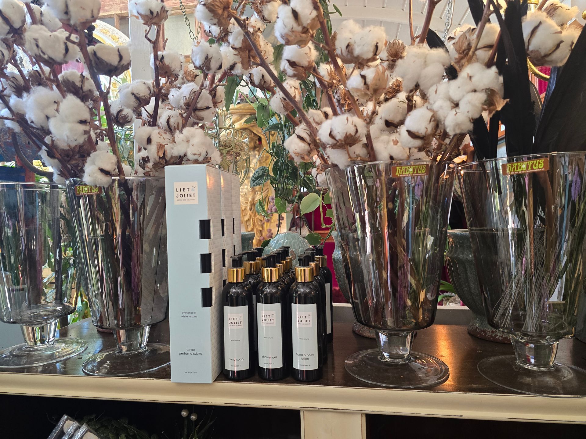 Eine Ausstellung von Vasen gefüllt mit Baumwollblumen und Parfümflaschen