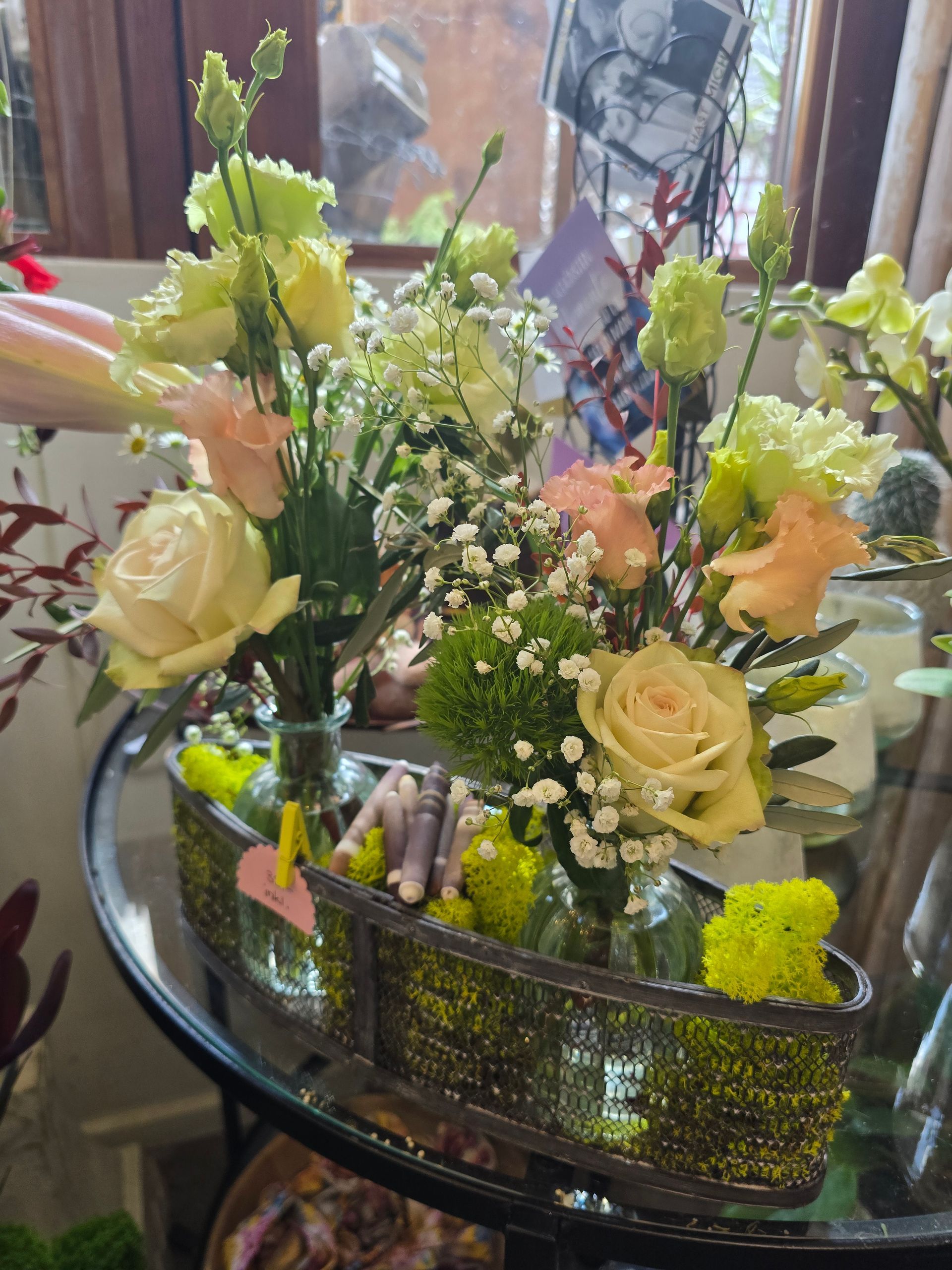 Auf einem Glastisch steht eine mit Blumen gefüllte Vase.