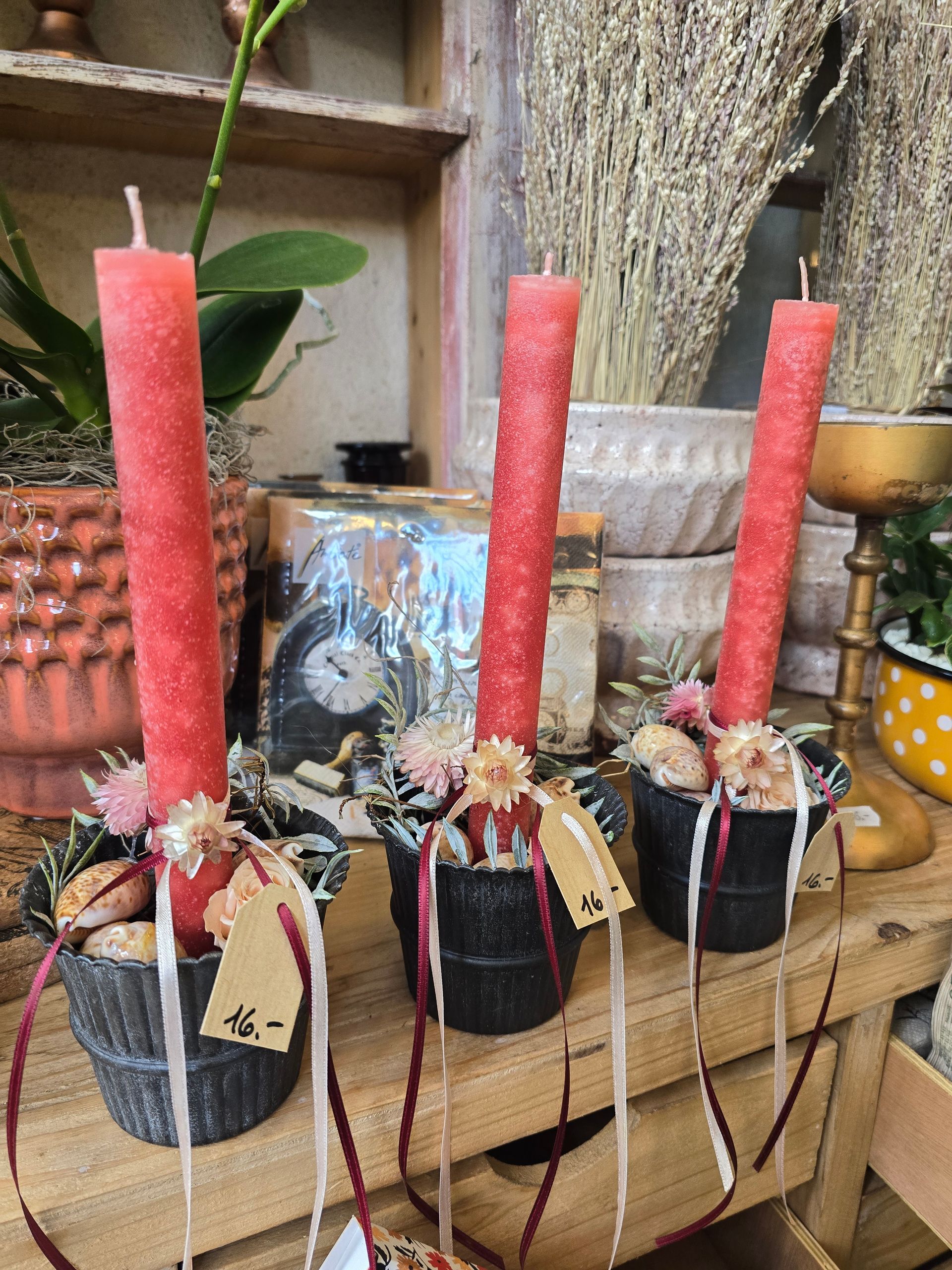 Drei rote Kerzen stehen auf einem Holztisch