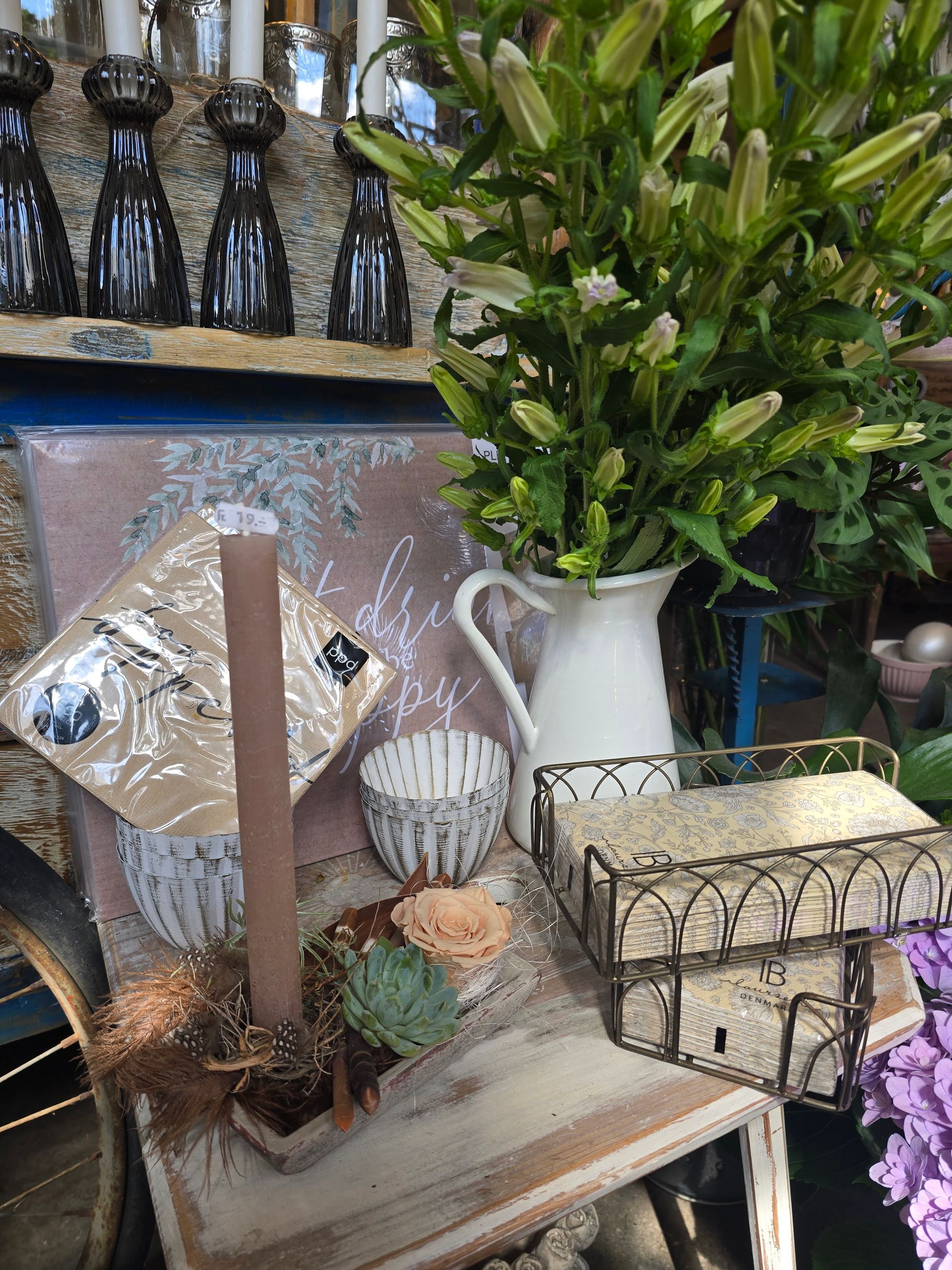 Ein Tisch mit einer Vase mit Blumen und Kerzen darauf.