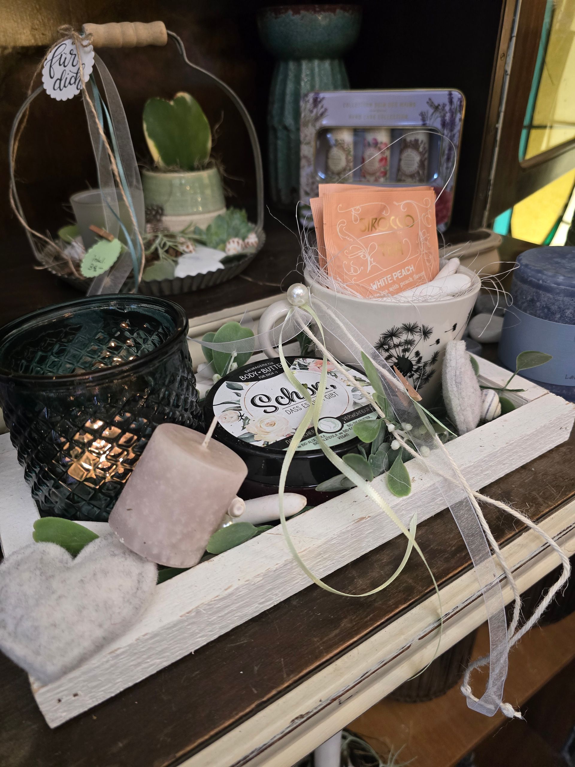 Ein Holztablett voller Kerzen und Pflanzen auf einem Tisch.