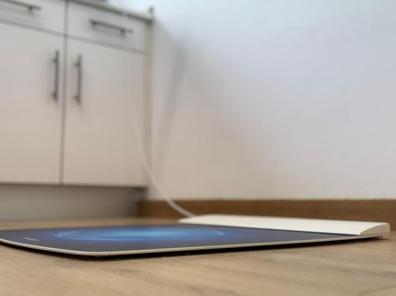 Una tableta está sobre un piso de madera en una cocina.