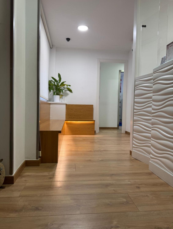 Un pasillo con suelo de madera y un banco en el medio.