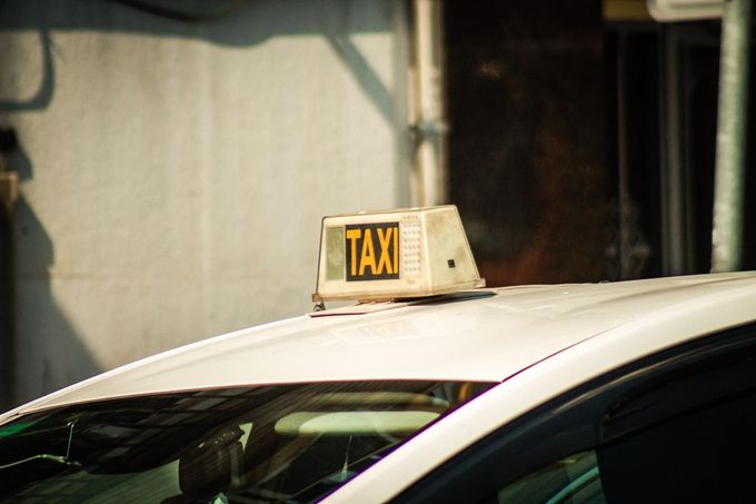 Letrero de taxi en la parte superior de un coche blanco frente a un edificio.