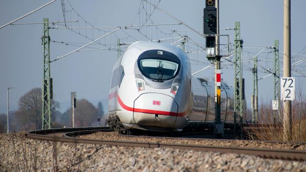 Un tren blanco de alta velocidad se aproxima por las vías del tren bajo un cielo despejado