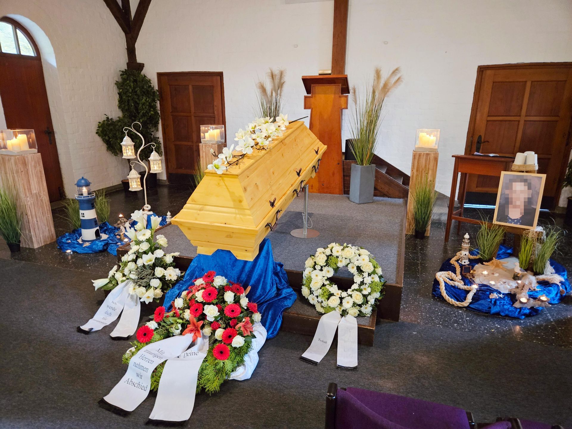 Ein gelber Sarg ist in einer Kirche von Blumen und Kerzen umgeben