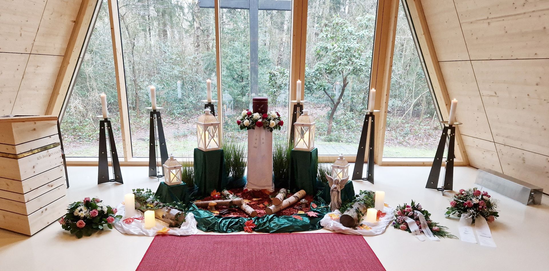 In der Mitte des Raumes steht ein Kreuz mit Blumen und Kerzen.