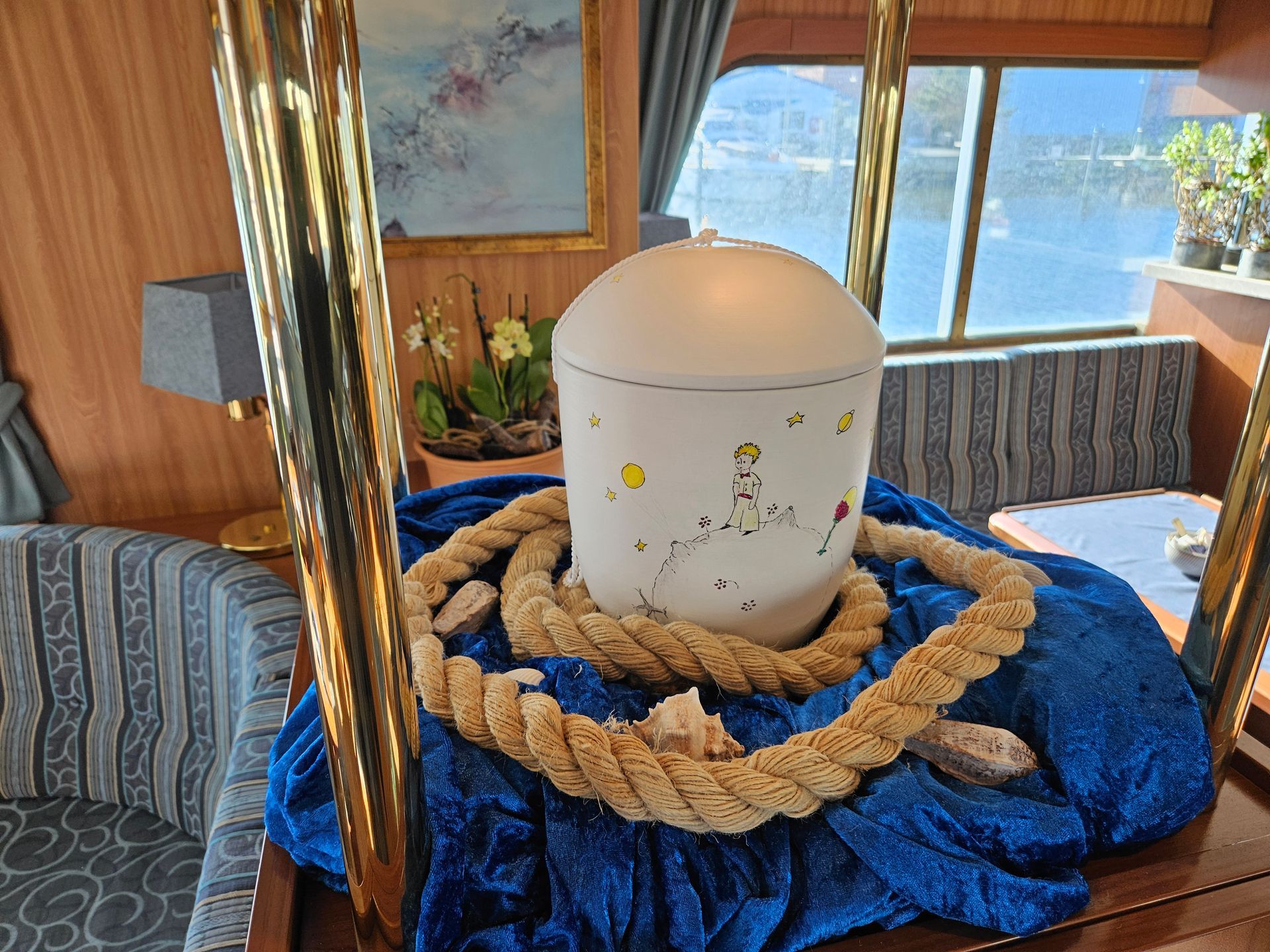 In einem Wohnzimmer ist eine weiße Urne von Seilen umgeben.